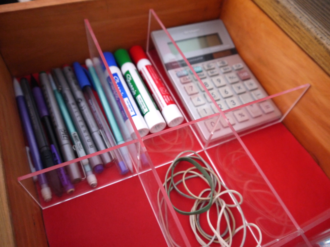 acrylic grid organizer on red mat in desk drawer